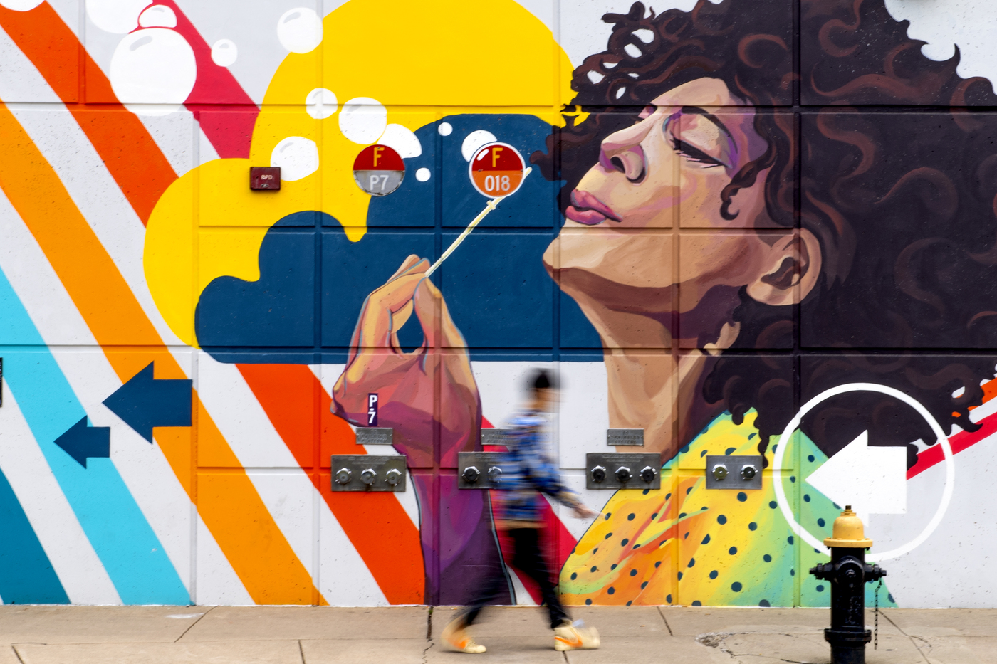 06/17/19 - BOSTON, MA. - A student passes the mural by Silvia Lopez Chavez on the MBTA wall across from Centennial Common on June 17, 2019.