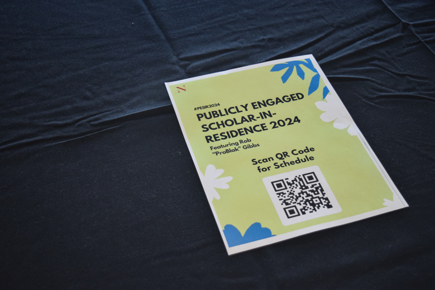 Photo shows the PESIR 2024 flyer on a table with a black tablecloth. The flyer is bright green.