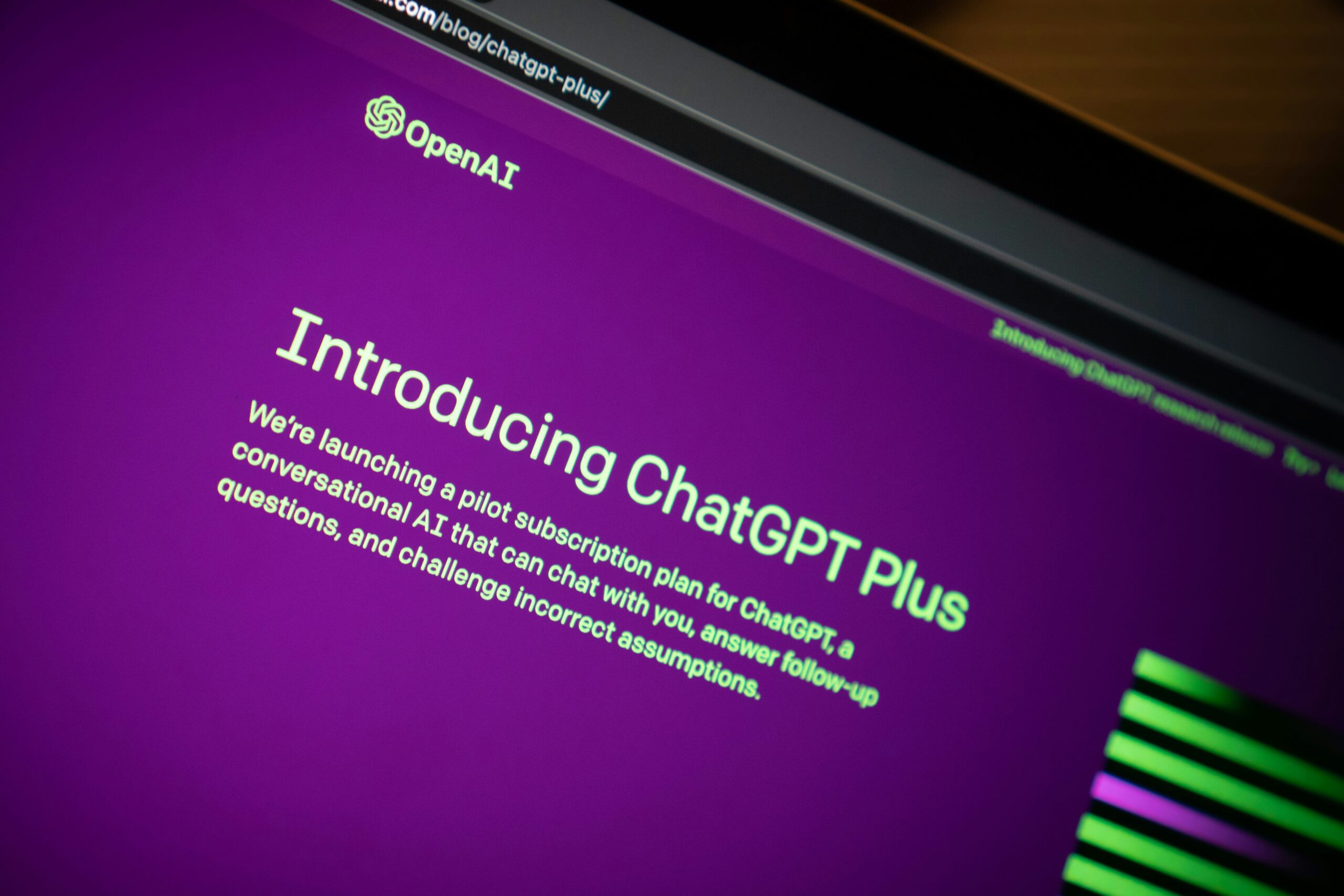 Image shows a computer on the ChatGPT website. The page says "Introducing ChatGPT Plus."
