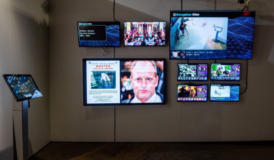 A dark gallery space with several TV screens on it.