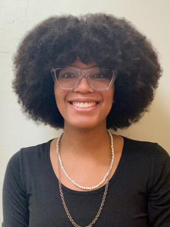 Headshot image of Melania Diaz. She is smiling and wears translucent framed glasses.
