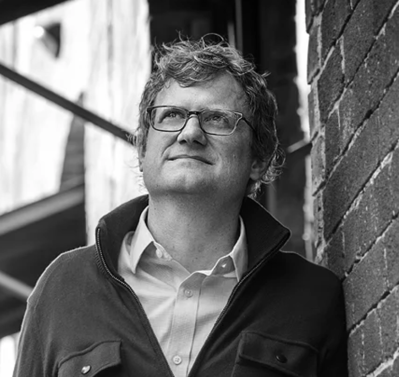 Black and white photo of Jonathan Donner, a white man with glasses wearing a quarter-zip sweatshirt.