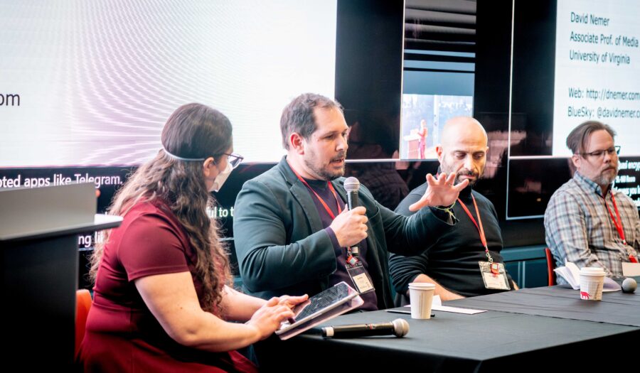 Image of Prof. John Wihbey speaking at the Center for Transformative Media's launch event, "Media in Motion," on Mar. 28, 2025. Wihbey is speaking into a microphone, and there is a bright TV behind him. He is sitting next to faculty members Michael Ann DeVito, Sina Fazelpour, and Derek Curry.