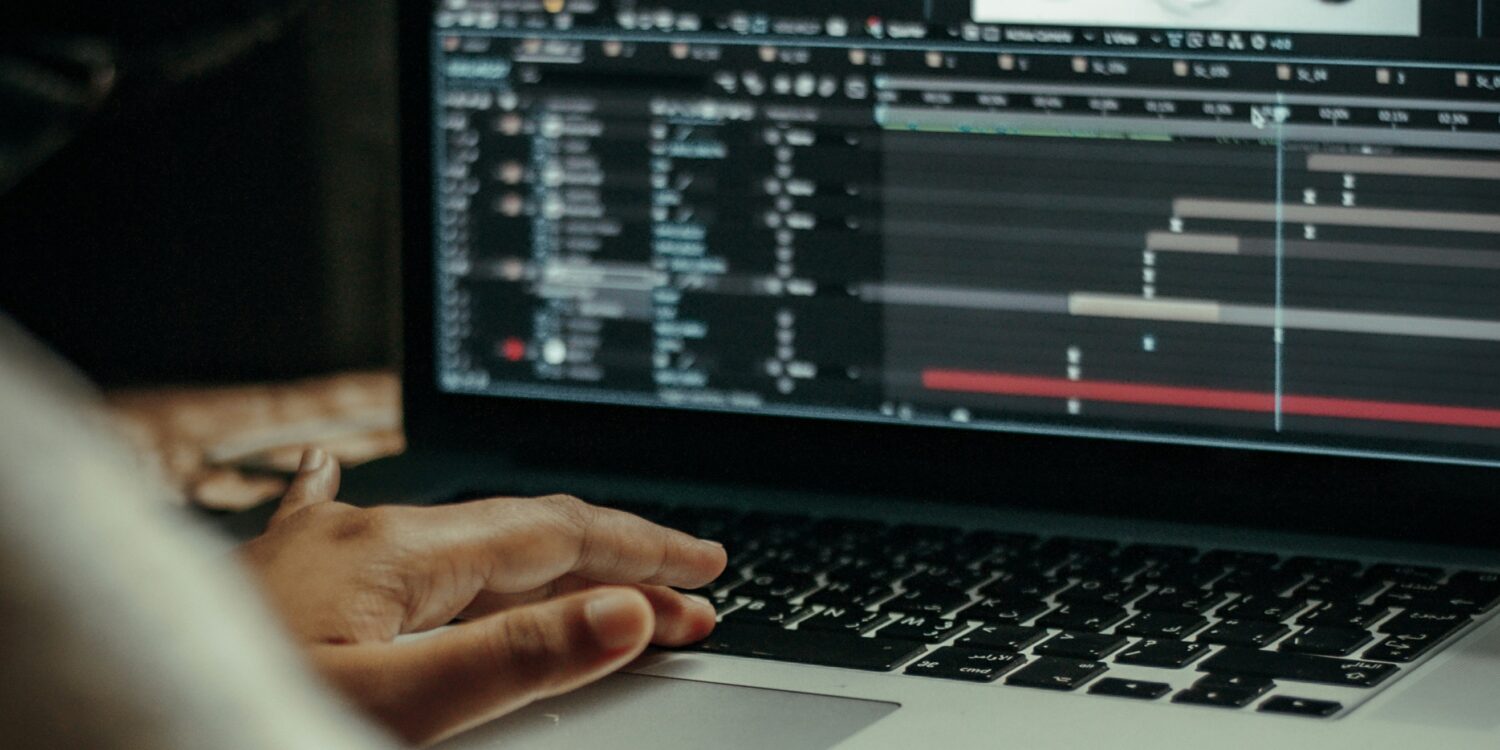 A woman's hands on her laptop keyboard. The laptop screen shows an animation software.