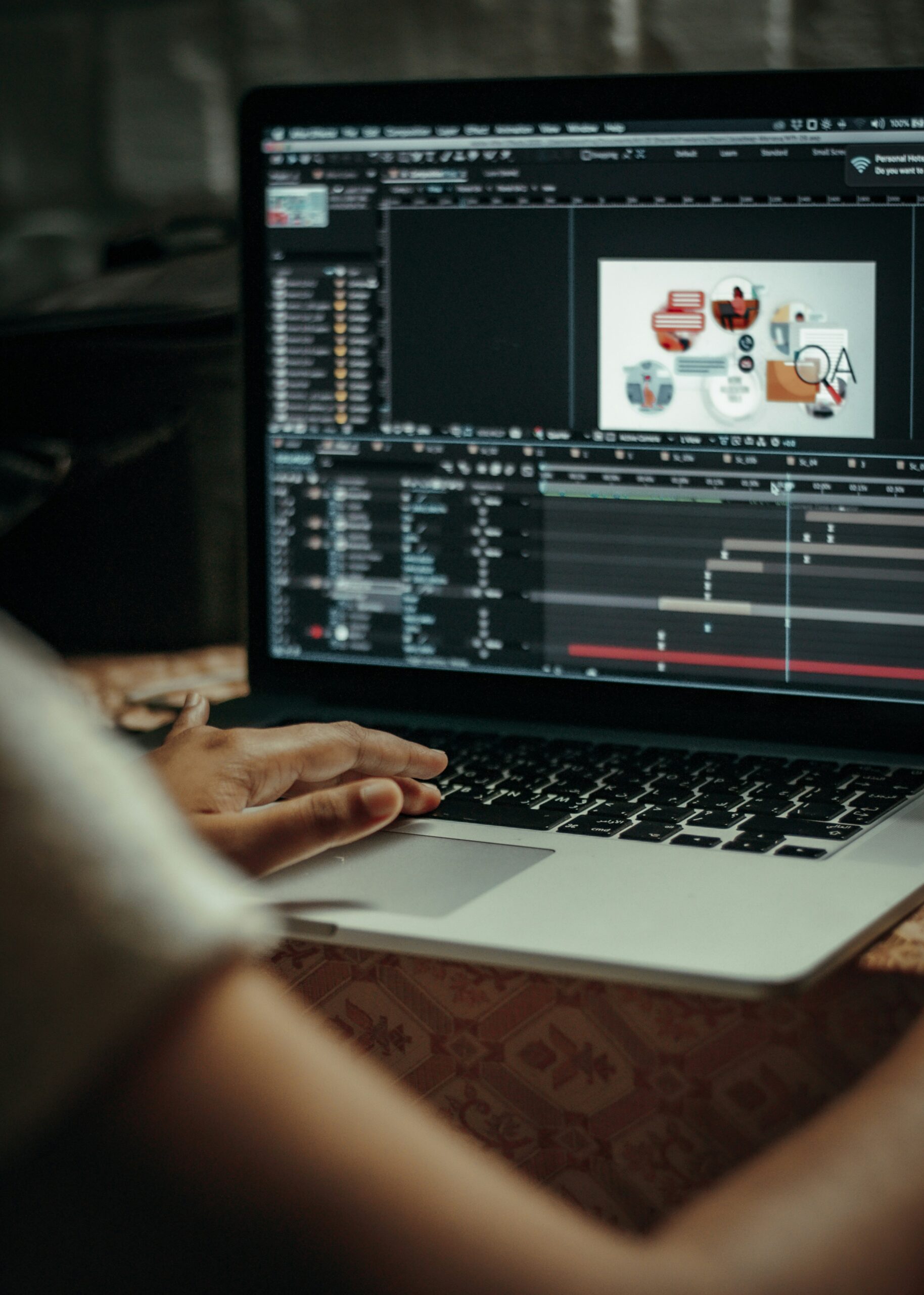 A woman's hands on her laptop keyboard. The laptop screen shows an animation software.