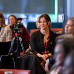 Image of Ragan Glover sitting in a lecture style room.
