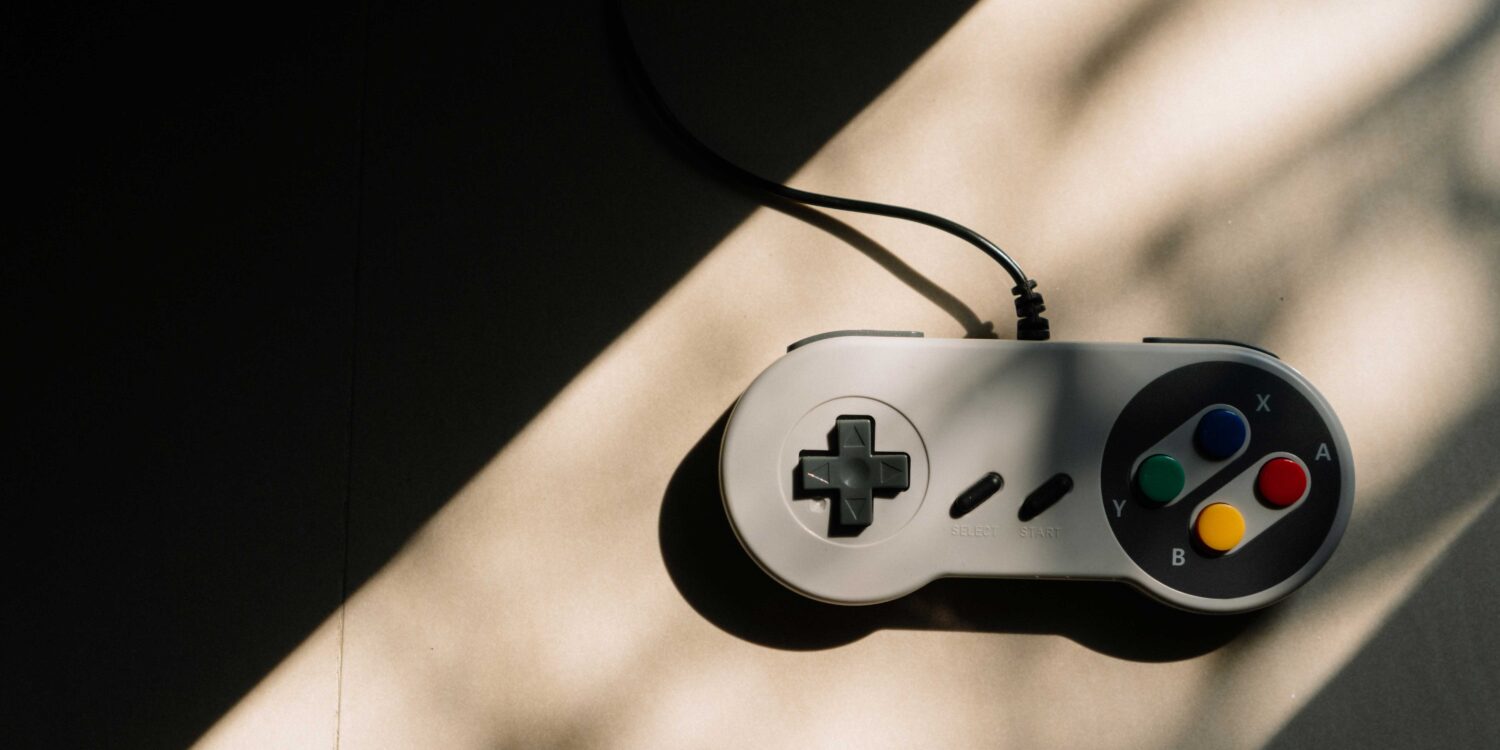 Image shows a vintage game controller with a large triangular shadow looming over the left side of the picture.