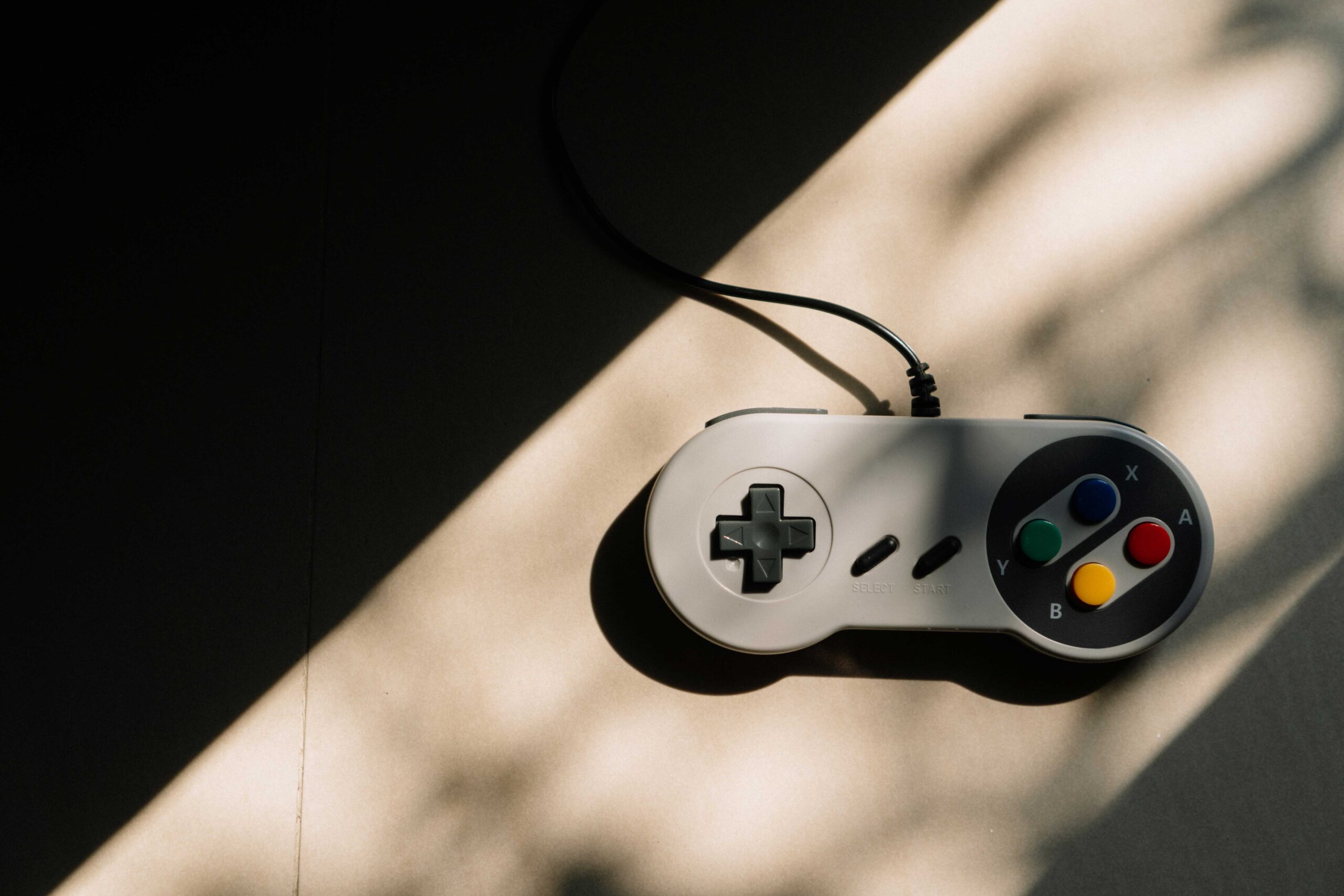 Image shows a vintage game controller with a large triangular shadow looming over the left side of the picture.
